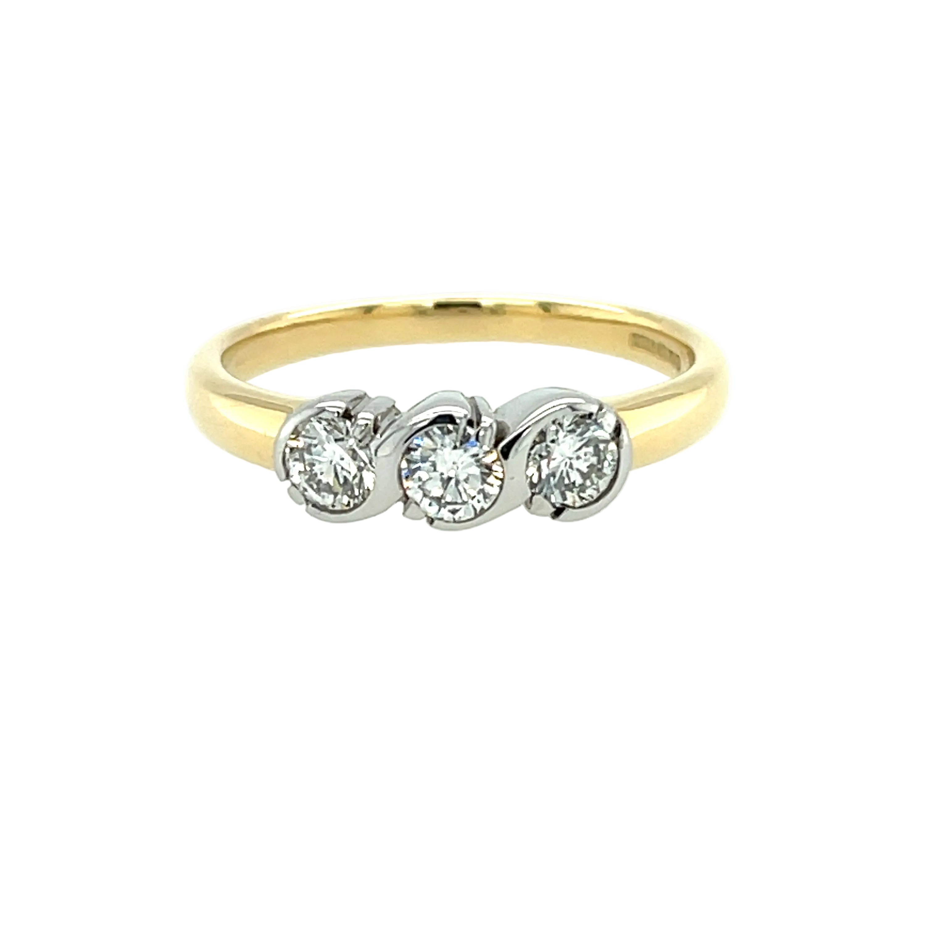 An 18ct yellow gold diamond three stone ring with a semi rub over trilogy setting in white gold on a contrasting yellow gold band.