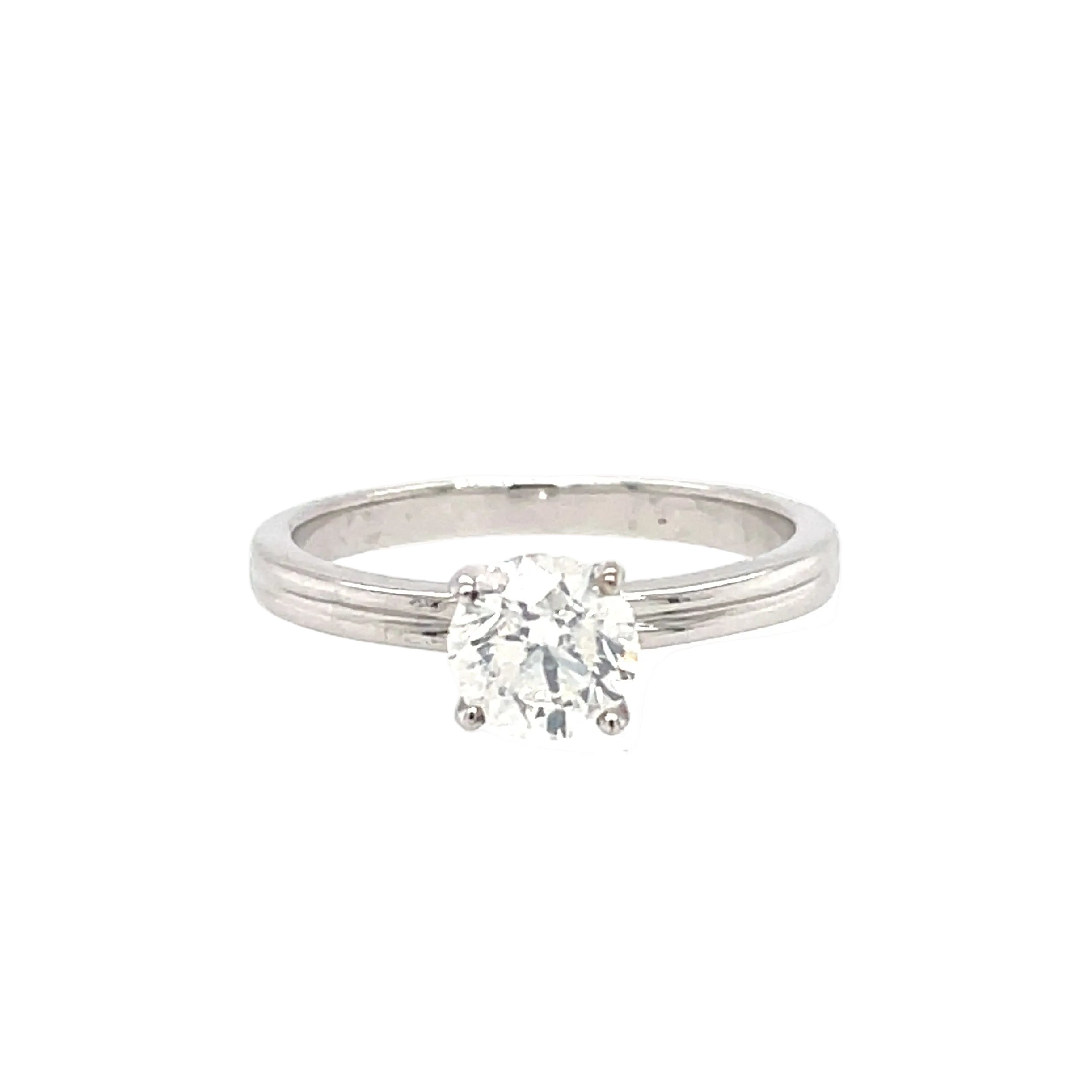 An 18ct white gold diamond solitaire engagement ring with a round brilliant cut diamond mounted in a four claw setting, extending to a 2mm wide band.