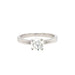 An 18ct white gold diamond solitaire engagement ring with a round brilliant cut diamond mounted in a four claw setting, extending to a 2mm wide band.